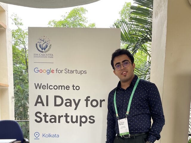 Aritra Neogi standing in front of the event banner